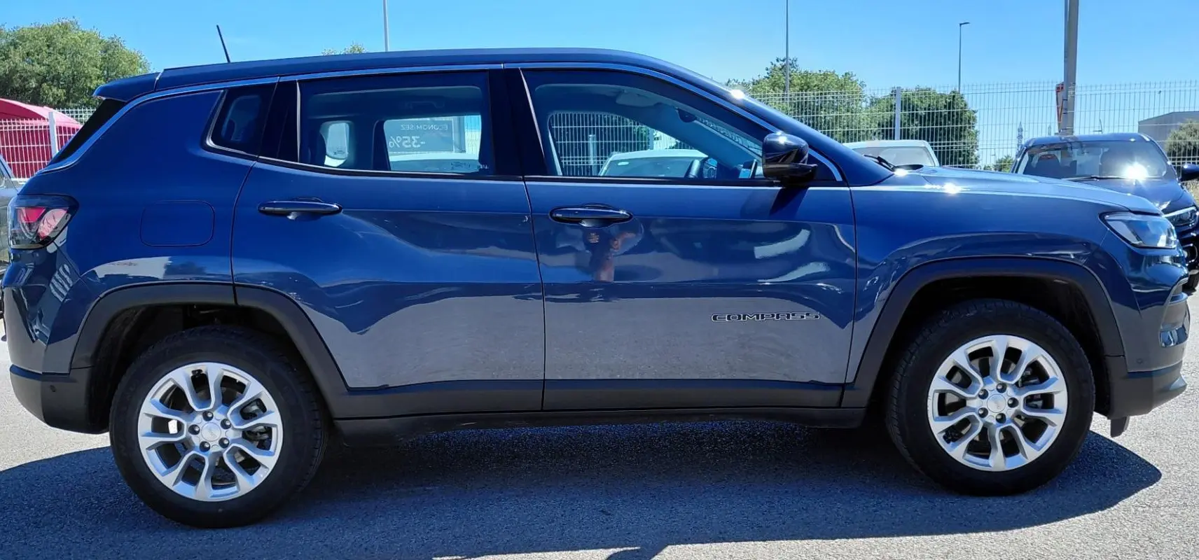Vue latérale droite d'un Jeep Compass bleu 2025 avec jantes alliage 18 pouces et logo Compass sur la porte.
