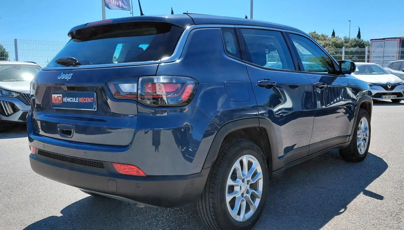 Vue 3/4 arrière droite d’un Jeep Compass bleu 2025 avec jantes alliage 18 pouces et feux arrière LED.