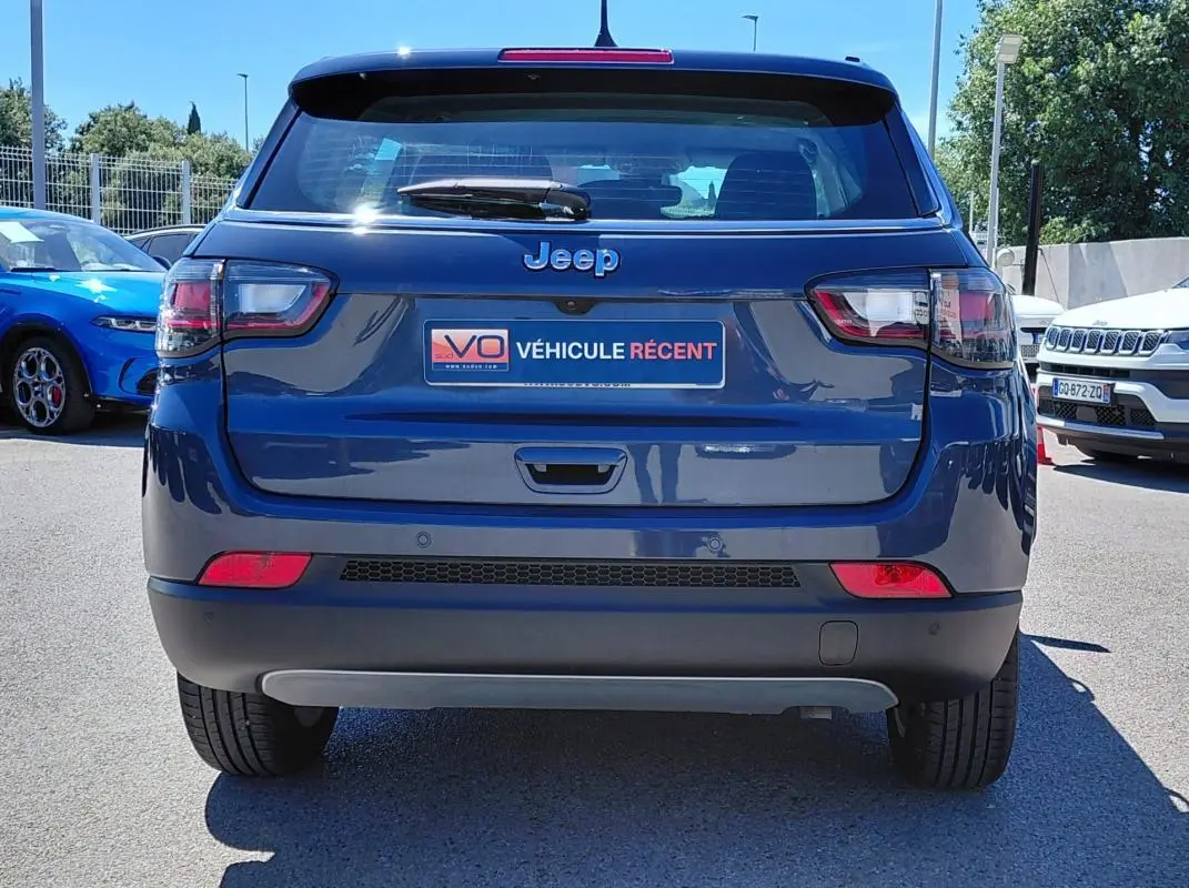 Vue arrière d’un Jeep Compass bleu 2025 avec feux LED et plaque « Véhicule récent » visible en extérieur.
