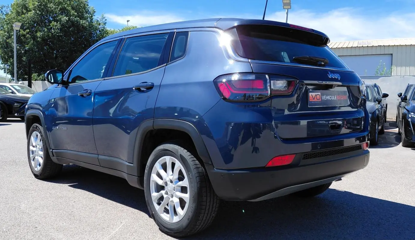 Jeep Compass bleu vue 3/4 arrière droit, jantes alliage 18 pouces et feux arrière LED visibles.