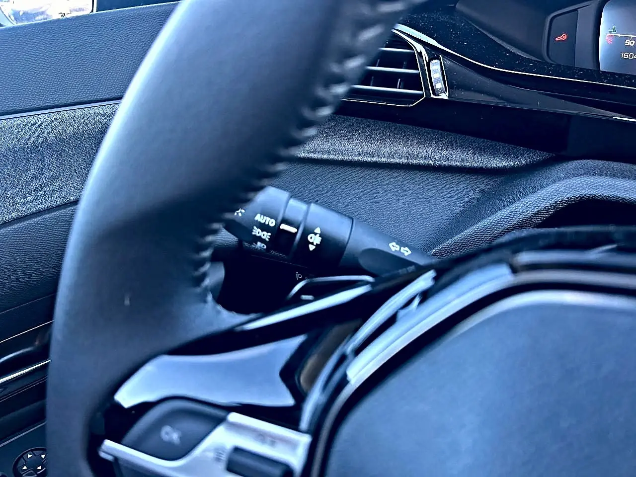 Gros plan sur le volant noir multifonction et la commande des phares de la Peugeot 308 1.5 BlueHDi 130 Allure EAT8.