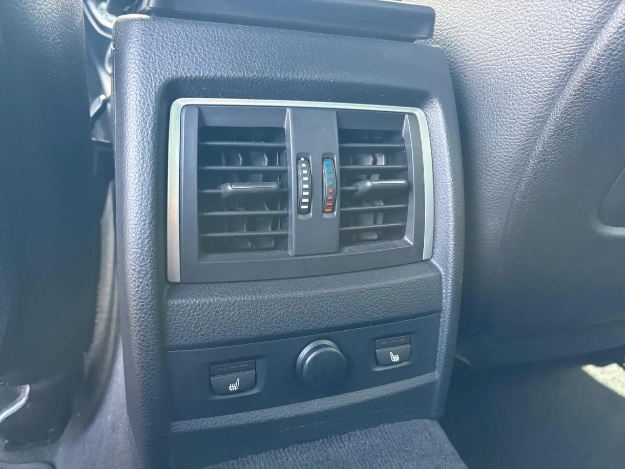 Détail des aérateurs arrière noirs avec commandes de chauffage des sièges dans une BMW Série 4 Gran Coupe noire.