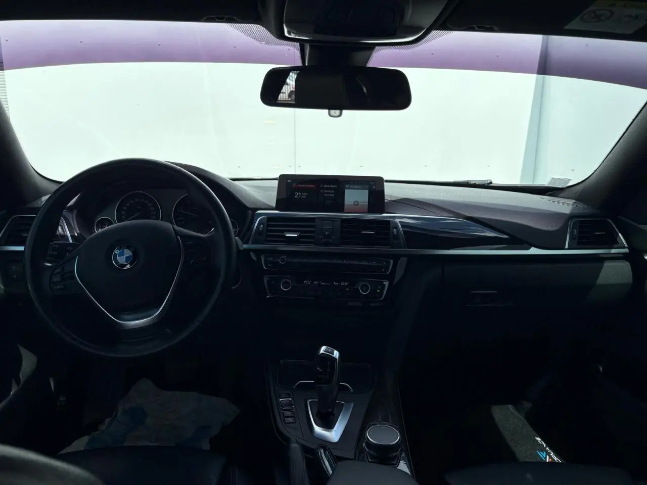 Vue intérieure avant du tableau de bord et volant cuir de la BMW Série 4 Gran Coupé noir avec écran central et levier de boîte automatique.