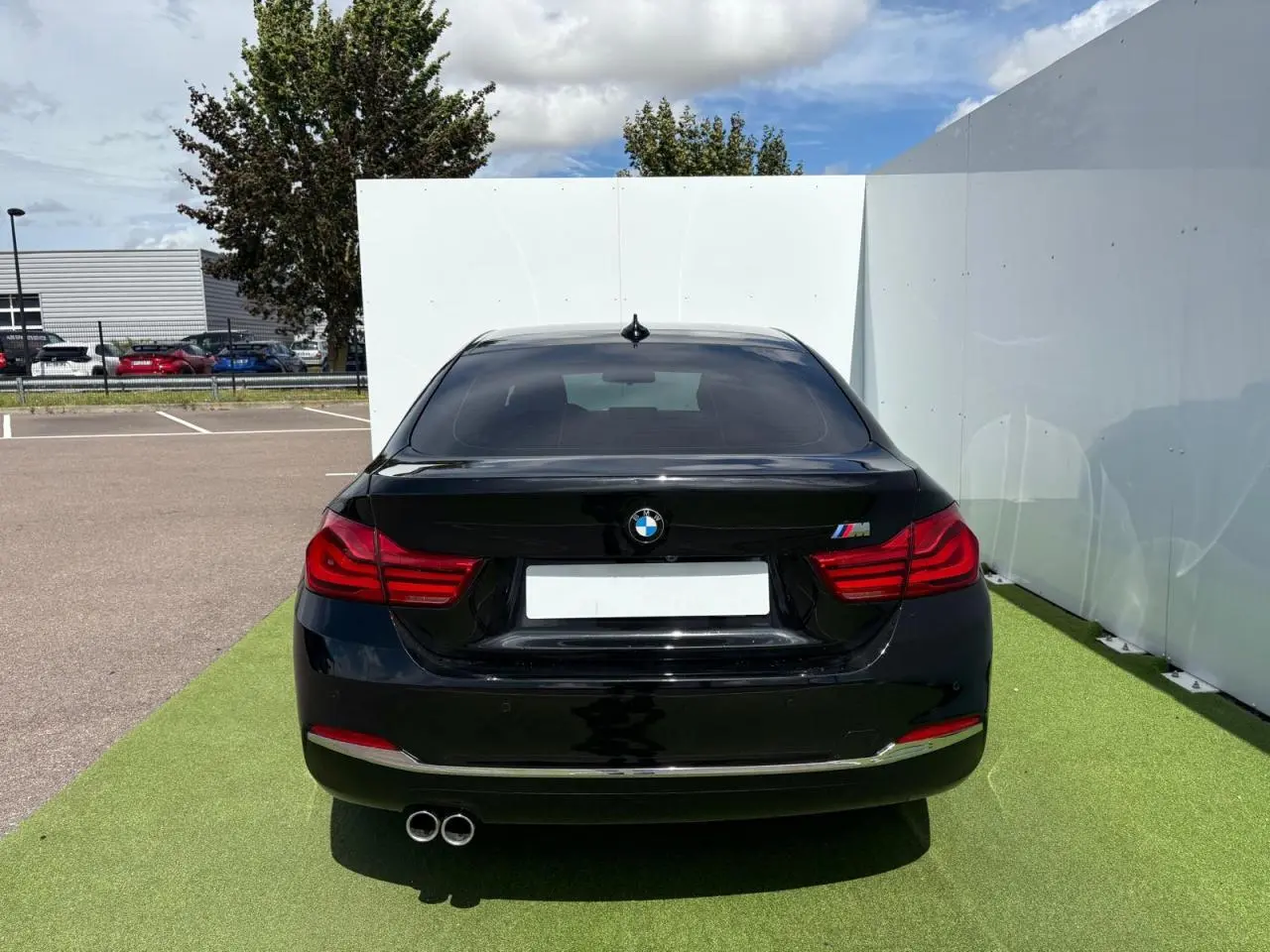 Vue arrière d'une BMW Série 4 Gran Coupé noire avec double sortie d'échappement et logo M sur le coffre.