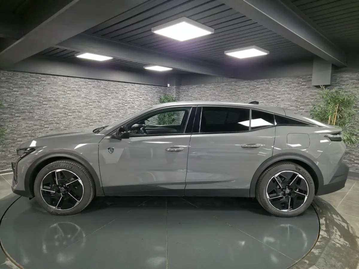 Profil droit de la Peugeot 408 gris Selenium 2024 hybride rechargeable avec jantes alliage 19 pouces et vitres teintées.
