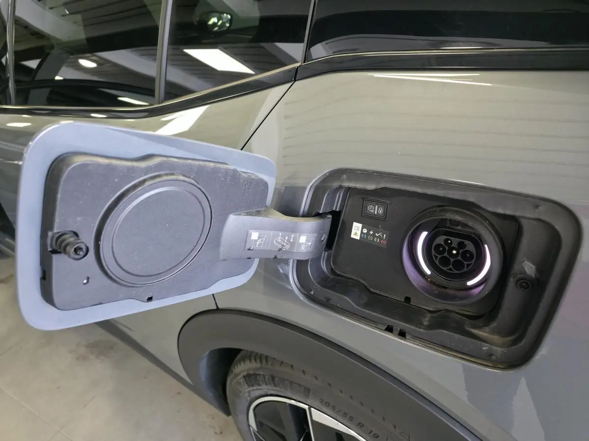 Prise de recharge ouverte côté gauche sur la carrosserie gris métallisé d'une Peugeot 408 hybride rechargeable 2024.