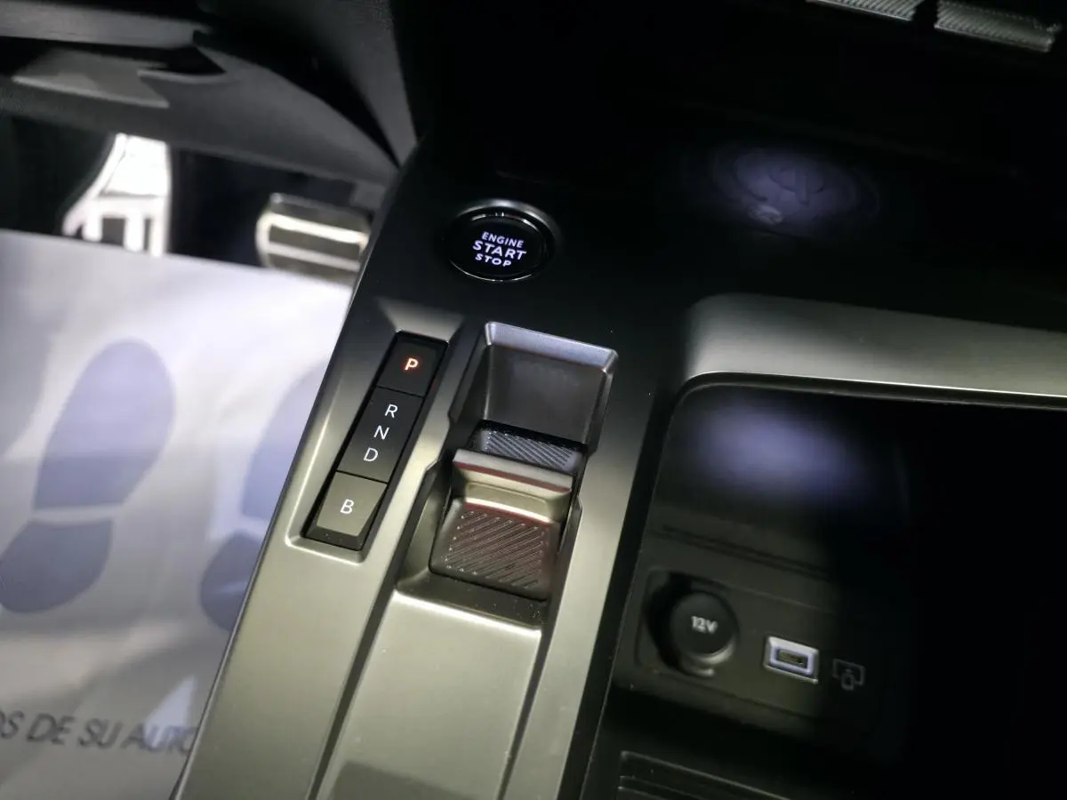 Gros plan sur la console centrale du Peugeot 408 gris, avec sélecteur de boîte auto, bouton start/stop et prise 12V visible.