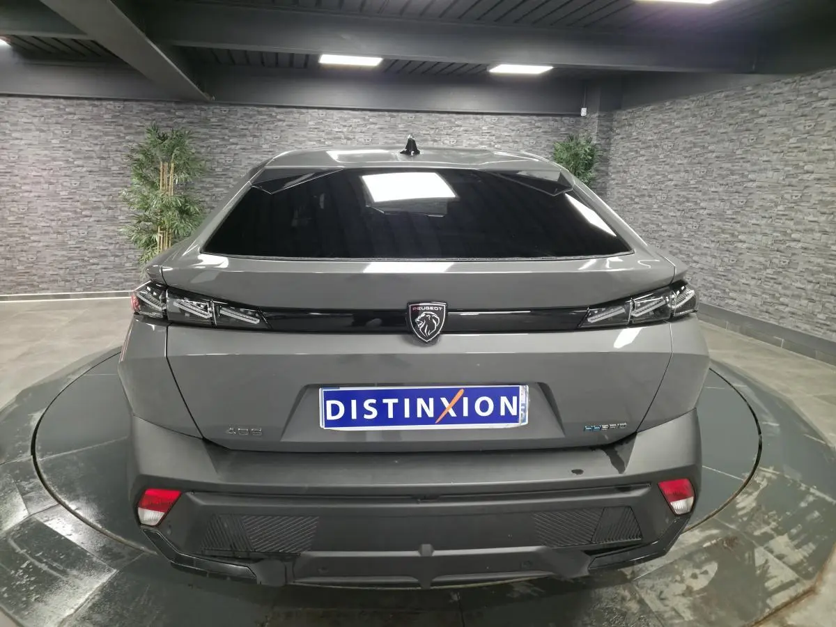 Vue arrière d'une Peugeot 408 gris Selenium hybride rechargeable avec feux arrière à effet griffe et logo noir brillant.