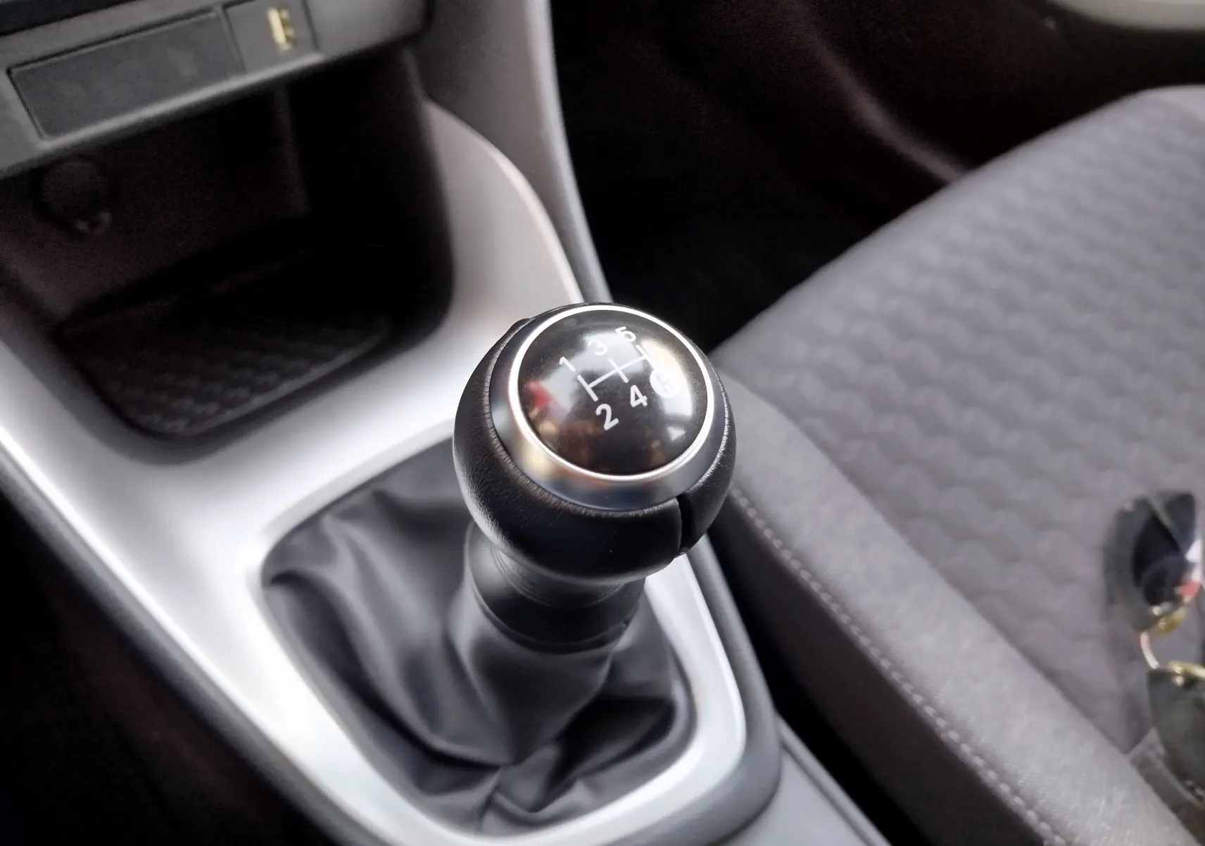 Gros plan sur le levier de vitesses manuel noir dans l’habitacle gris d’une Toyota Yaris blanche 2023.