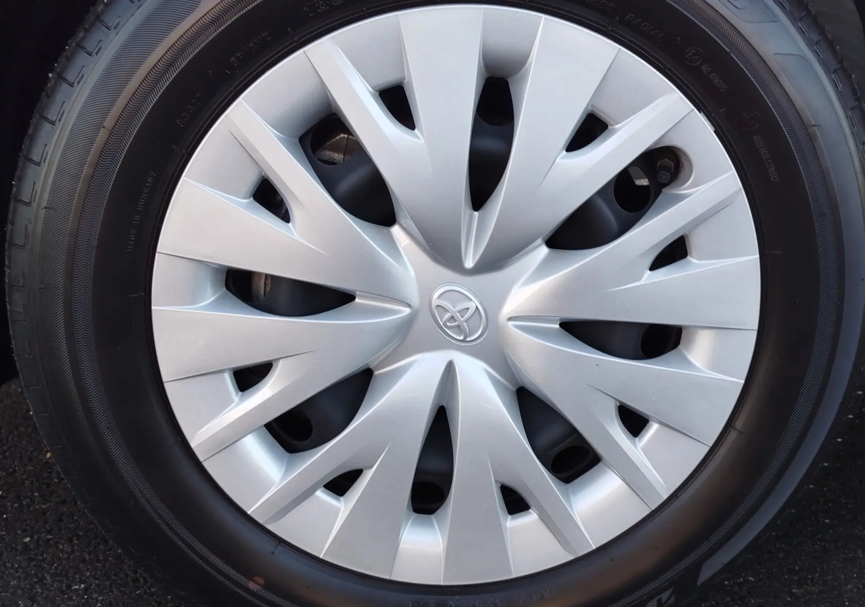 Gros plan sur la jante argentée avec logo Toyota au centre d'une Toyota Yaris blanche 2023.