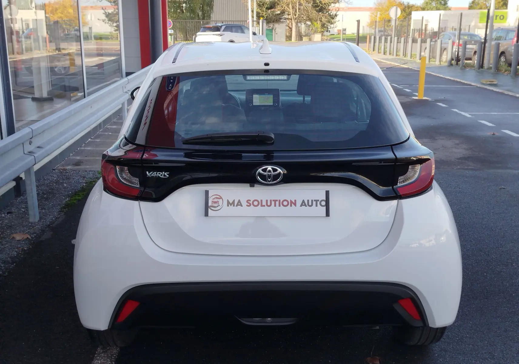 Vue arrière d'une Toyota Yaris blanche pur 2023 avec toit noir et feux arrière distinctifs en forme de boomerang.