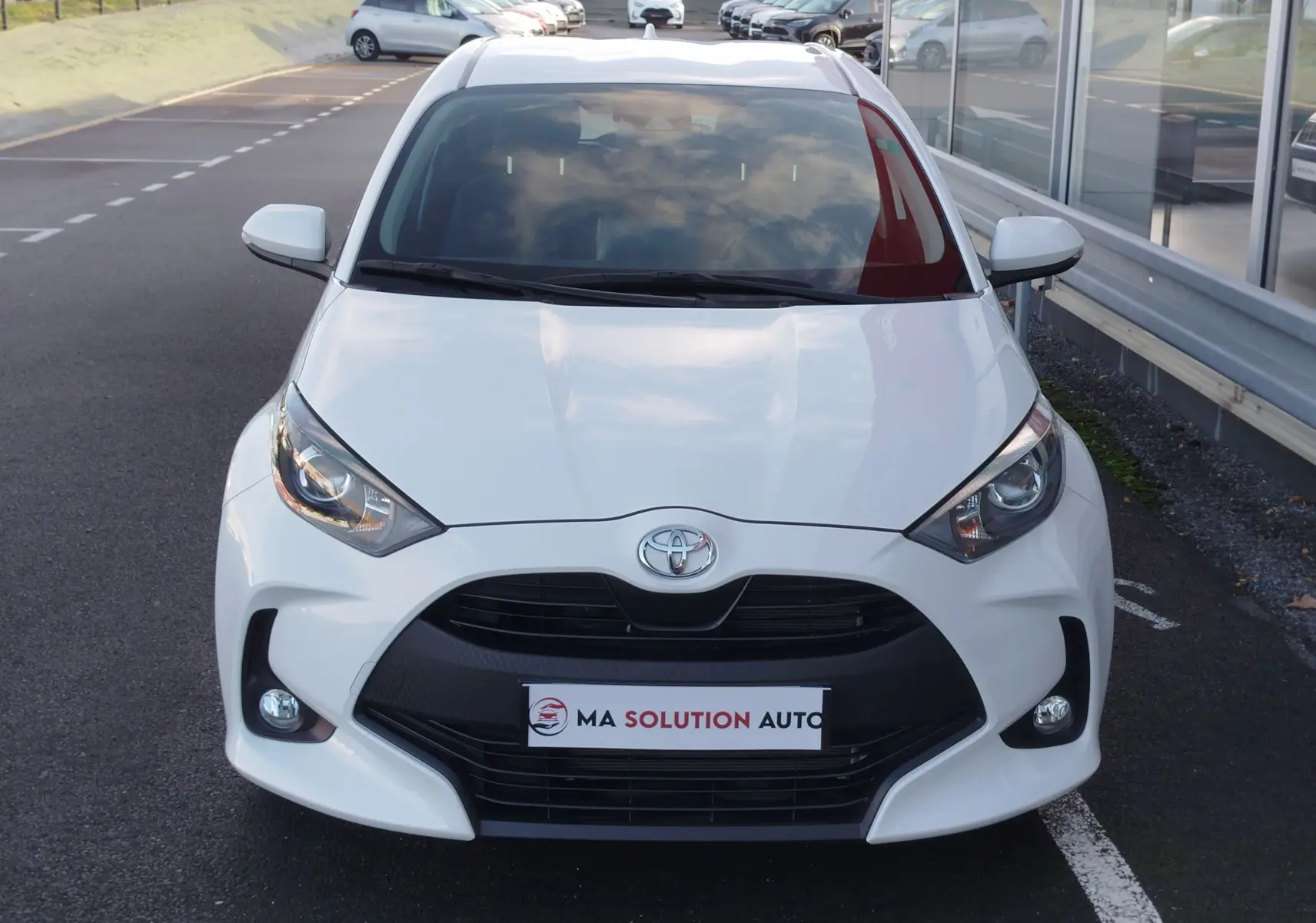 Vue avant d'une Toyota Yaris blanche pure 2023, mettant en valeur sa calandre noire et ses phares LED distinctifs.