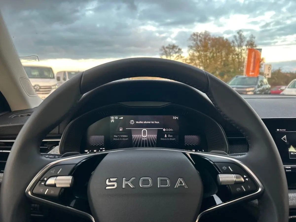 Vue intérieure centrée sur le volant cuir noir du Skoda Kamiq 2025 avec tableau de bord digital allumé.