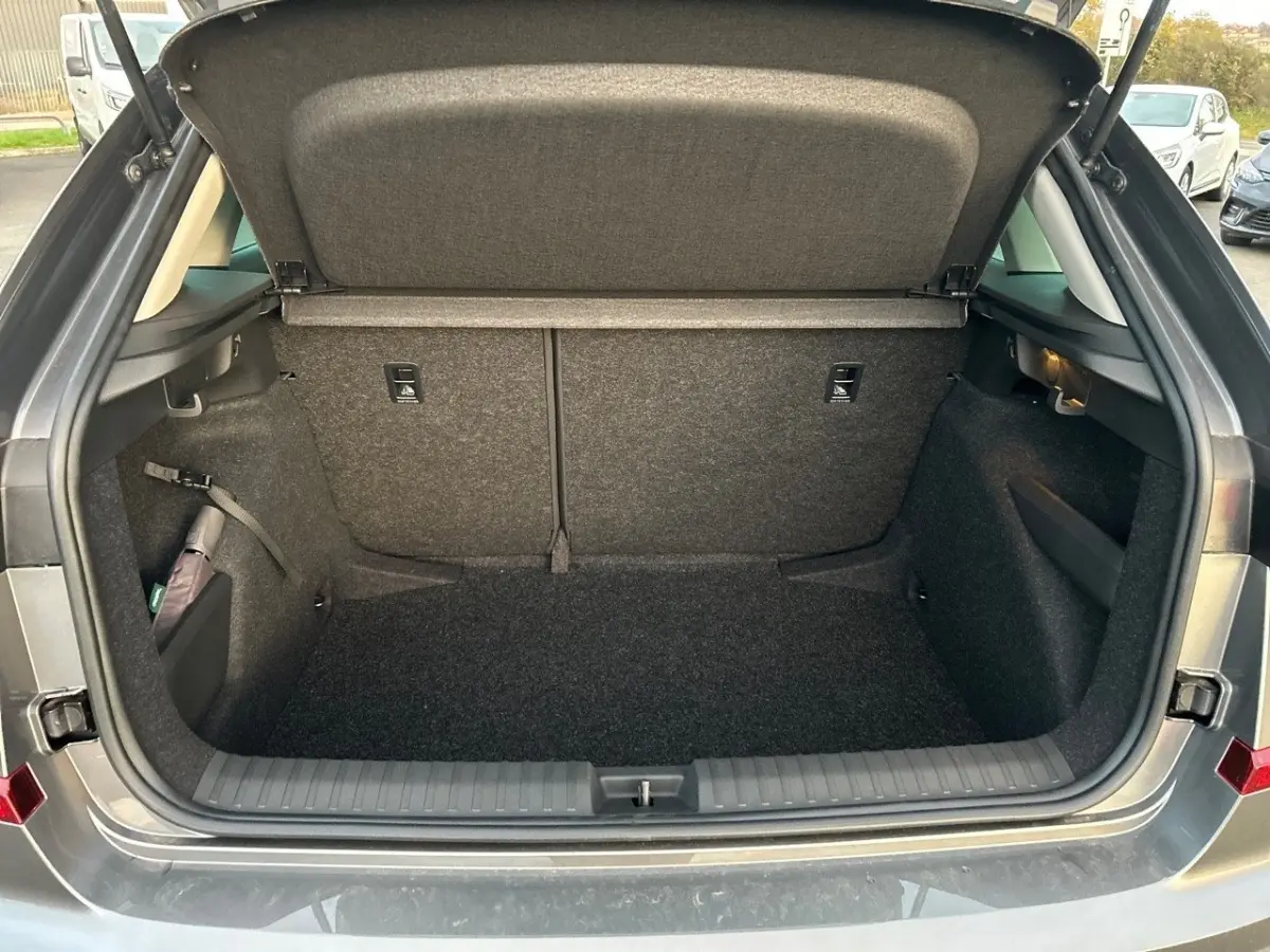 Coffre ouvert gris clair du Skoda Kamiq 2025, vue arrière montrant l'espace de chargement vide et la tablette de coffre.