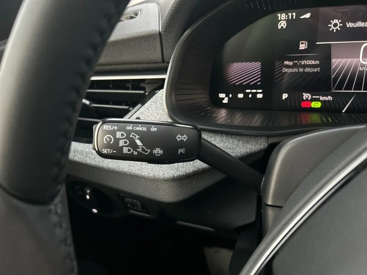 Gros plan sur la manette de régulateur de vitesse à gauche du volant du Skoda Kamiq gris clair, avec tableau de bord numérique en arrière-plan.