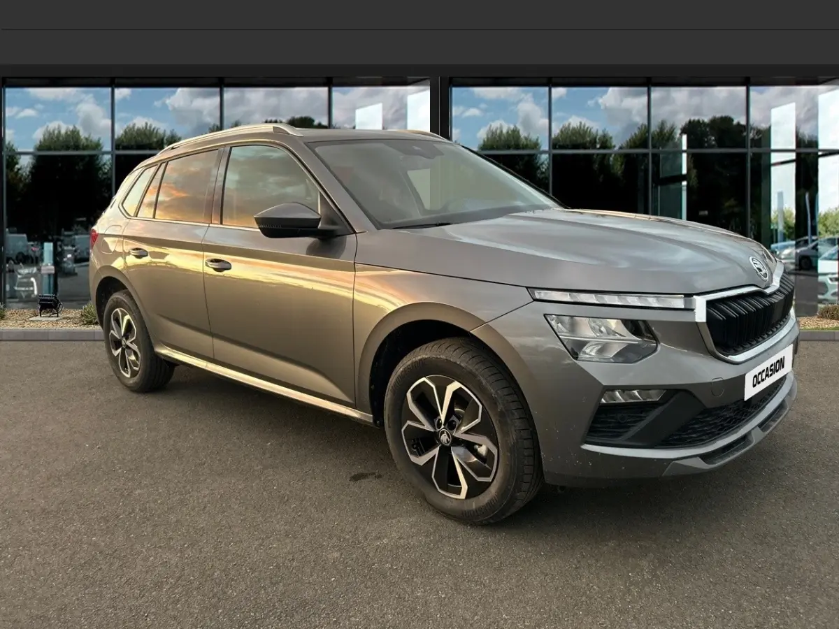Skoda Kamiq gris clair vu en 3/4 avant droit, avec calandre noire et jantes alliage bicolores.
