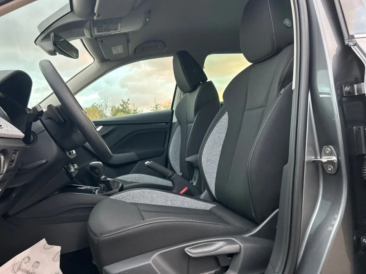 Intérieur de la Skoda Kamiq gris clair, vue côté conducteur montrant sièges tissu noir et gris avec surpiqûres blanches.