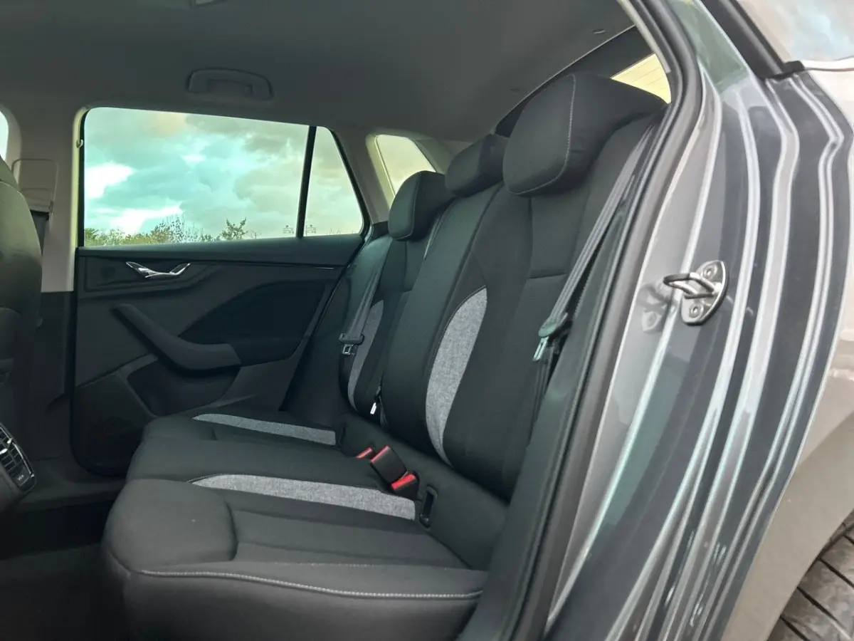 Vue intérieure côté droit sur la banquette arrière noire et grise du Skoda Kamiq gris clair 2025 avec porte ouverte.