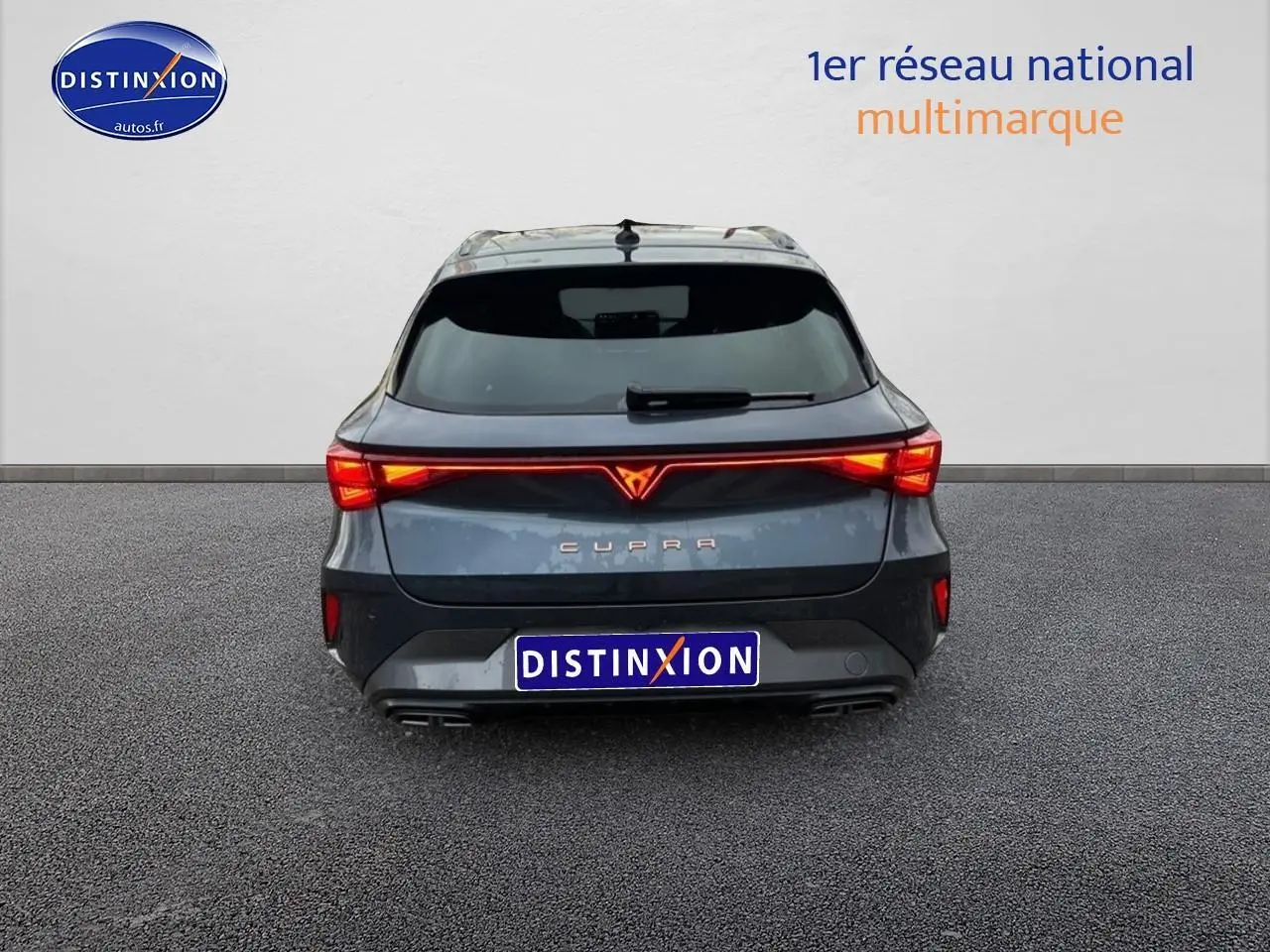 Vue arrière d'une CUPRA LEON ST 2025 gris magnétique avec feux arrière LED allumés et double sortie d'échappement.