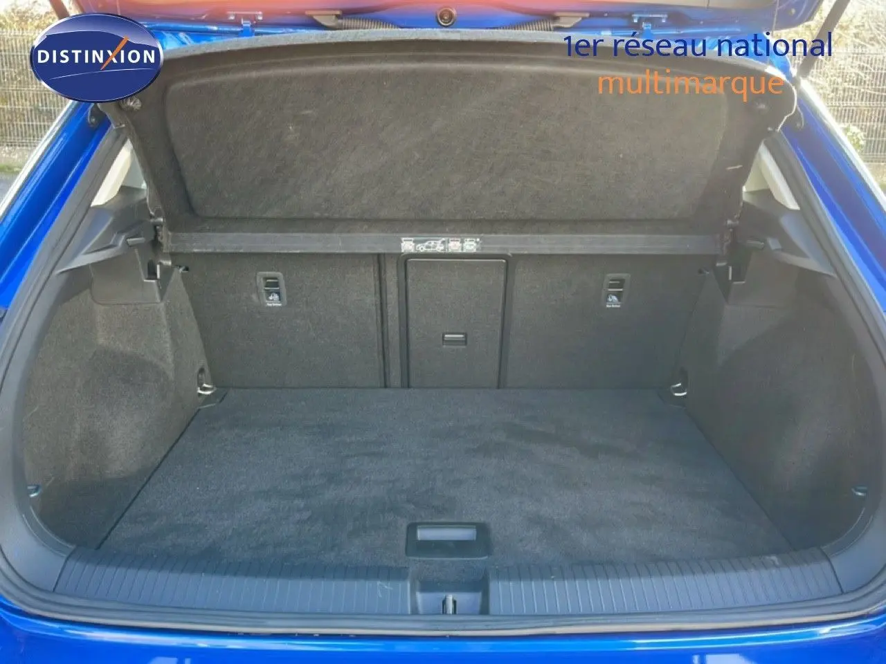 Coffre ouvert vu de l'arrière d'un Volkswagen T-Roc bleu Ravenna, montrant un espace de chargement propre et spacieux.