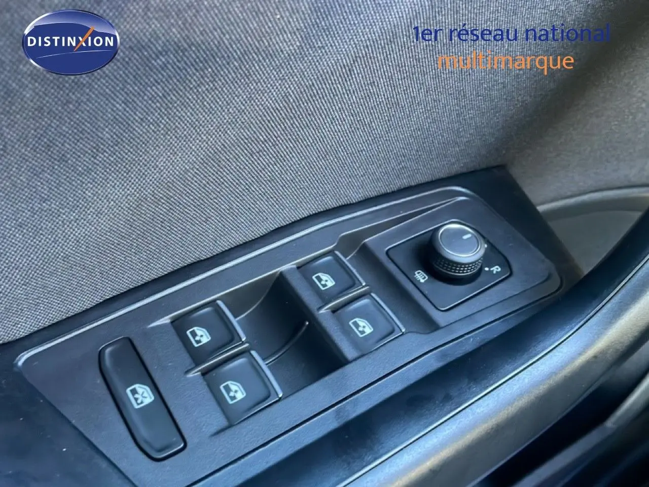 Gros plan sur les commandes des vitres électriques et du réglage des rétroviseurs côté gauche d’un Volkswagen T-Roc bleu Ravenna.