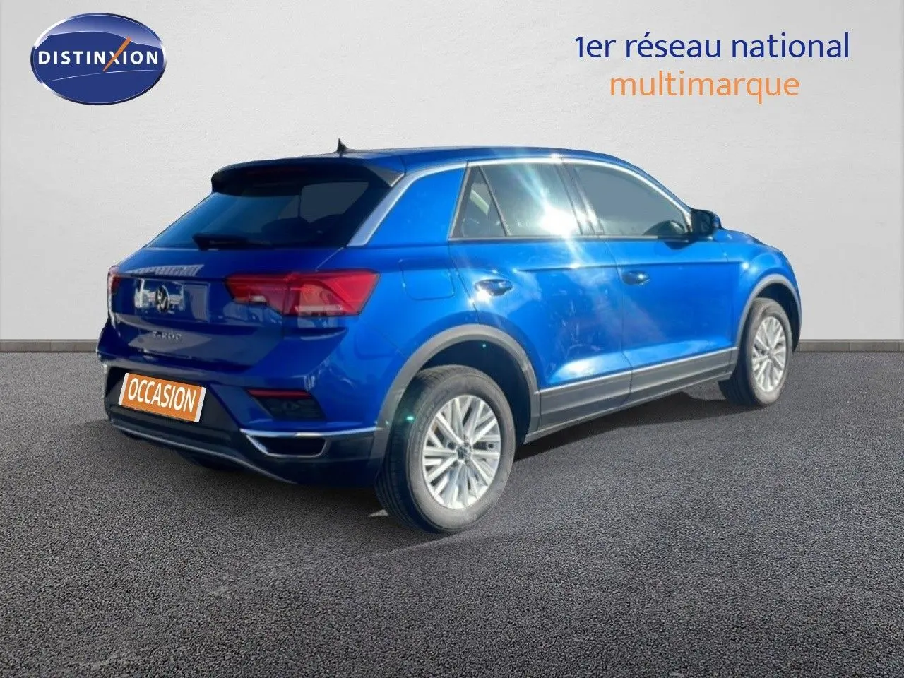 Vue 3/4 arrière droite d'un Volkswagen T-Roc bleu Ravenna métallisé sur fond neutre, avec jantes alliage et feux LED.