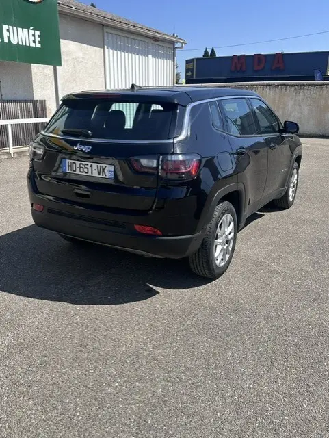Vue 3/4 arrière droite du Jeep Compass noir 2025 avec jantes alliage 18 pouces, sur parking extérieur ensoleillé.