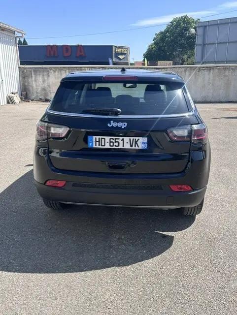 Vue arrière d'un Jeep Compass noir 2025 garé, mettant en valeur ses feux LED et sa silhouette compacte.