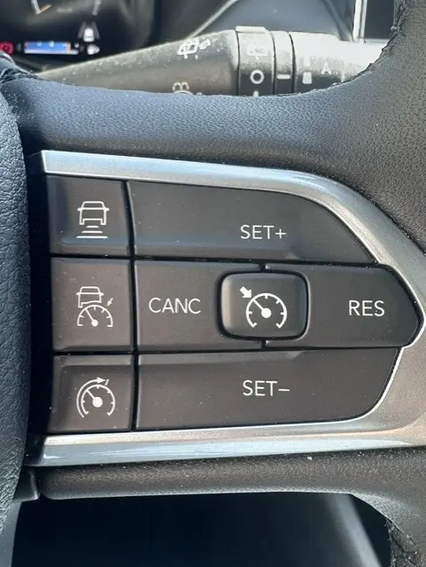 Gros plan sur les commandes du régulateur de vitesse au volant du Jeep Compass noir 2025, version e-Hybrid Altitude.