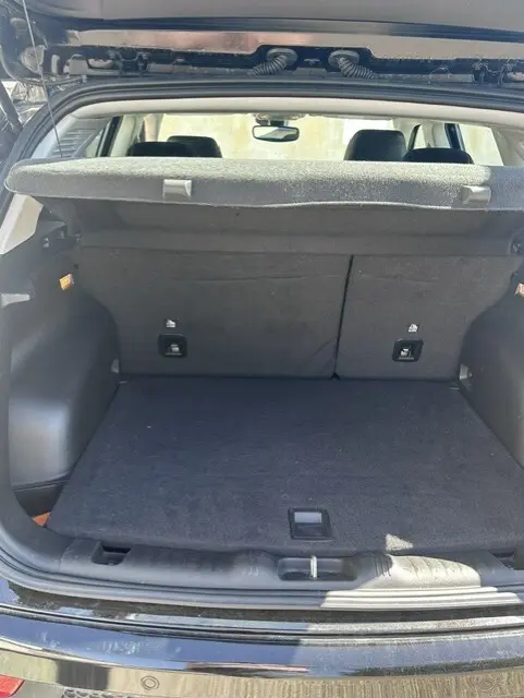 Coffre ouvert en vue arrière d’un Jeep Compass noir 2025, montrant un espace de chargement propre avec cache-bagages relevé.