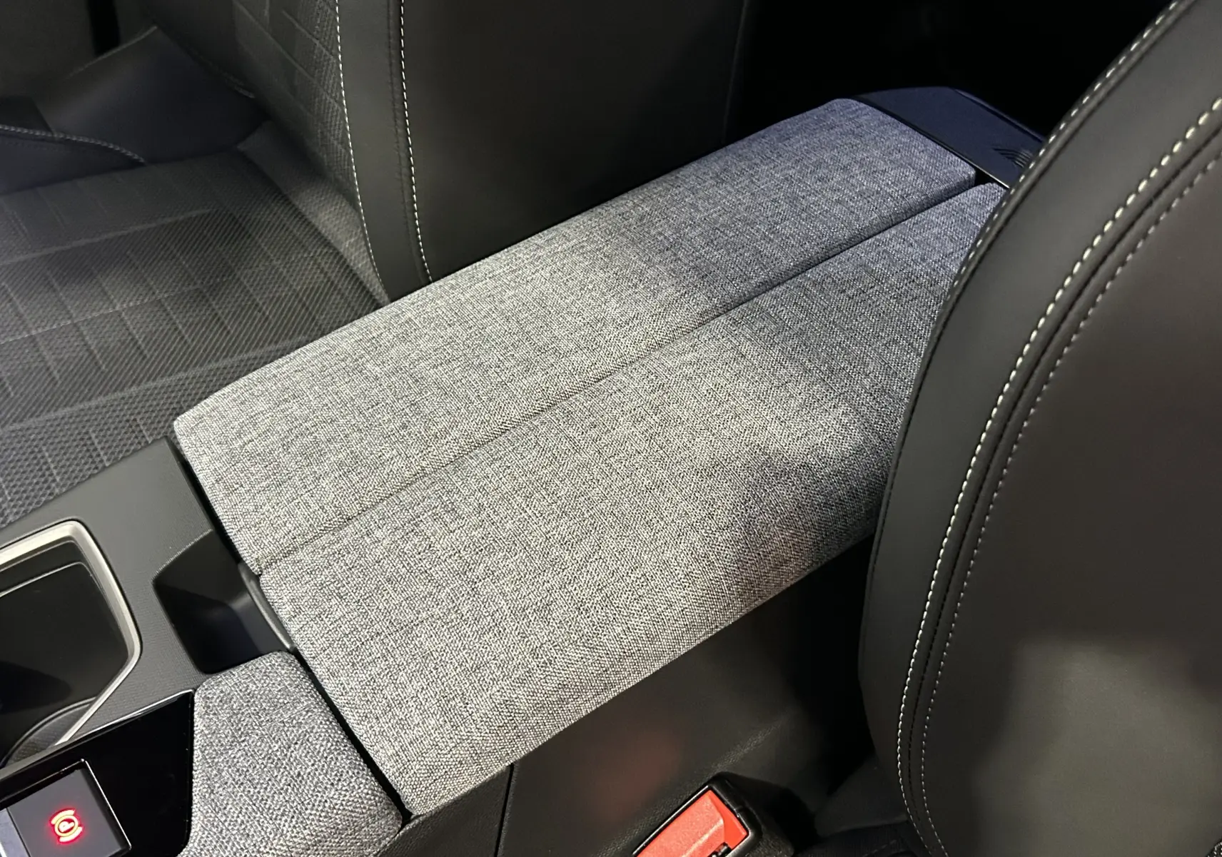 Gros plan sur l'accoudoir central en tissu gris clair entre les sièges avant en cuir noir du Peugeot 5008 2025.