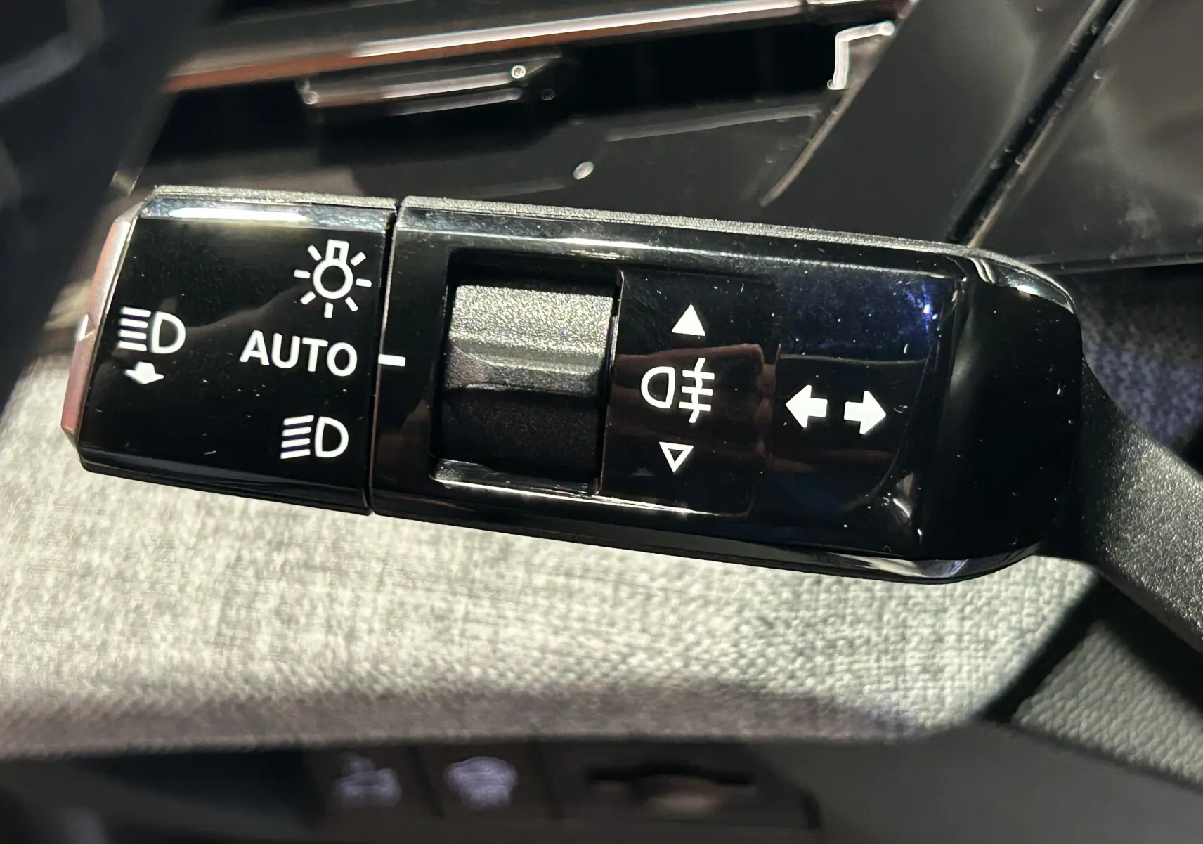 Gros plan sur la commande des feux automatiques et clignotants dans l’habitacle du Peugeot 5008 gris Artense 2025.