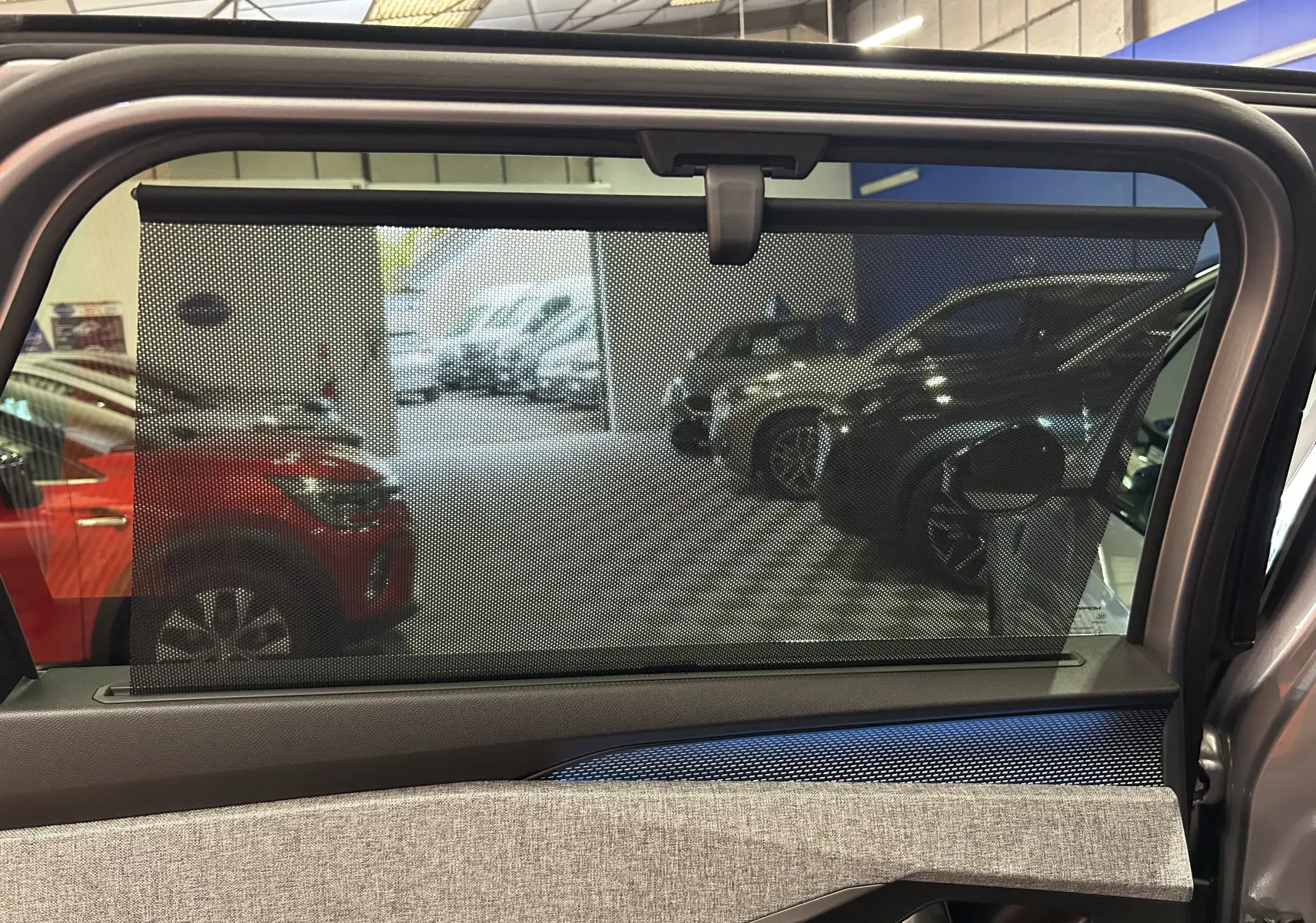 Vue intérieure de la porte arrière droite du Peugeot 5008 gris Artense avec pare-soleil intégré et tissu clair.