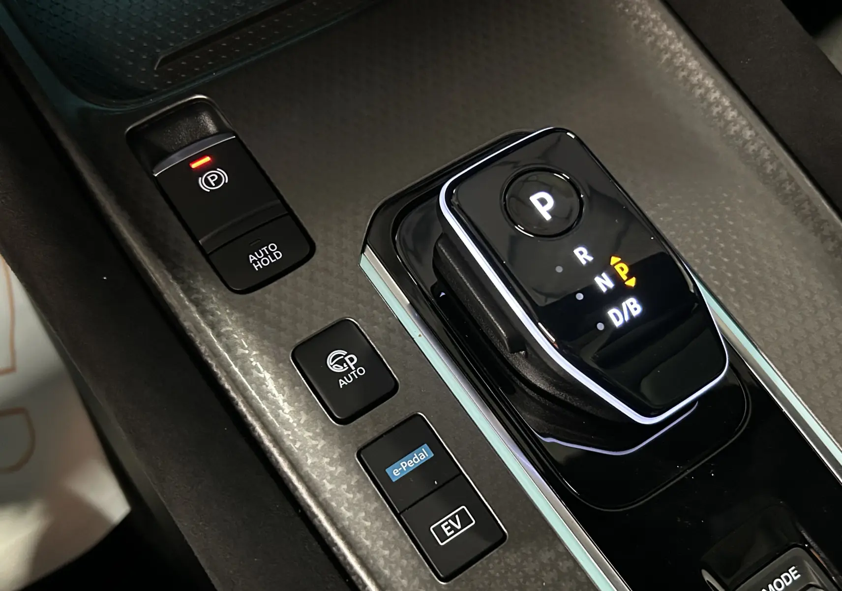 Gros plan sur la console centrale du Nissan Qashqai gris céramique, montrant la commande de boîte auto et les boutons e-Pedal et EV.