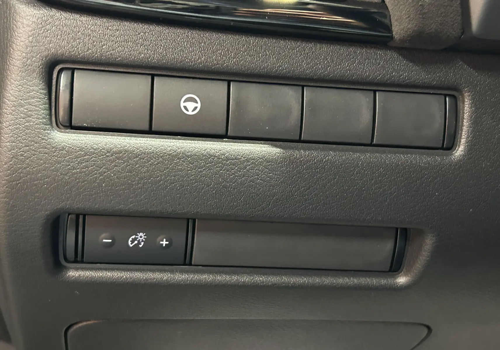 Boutons de réglage du volant et de l'éclairage du tableau de bord sur le côté gauche intérieur du Nissan Qashqai gris céramique.