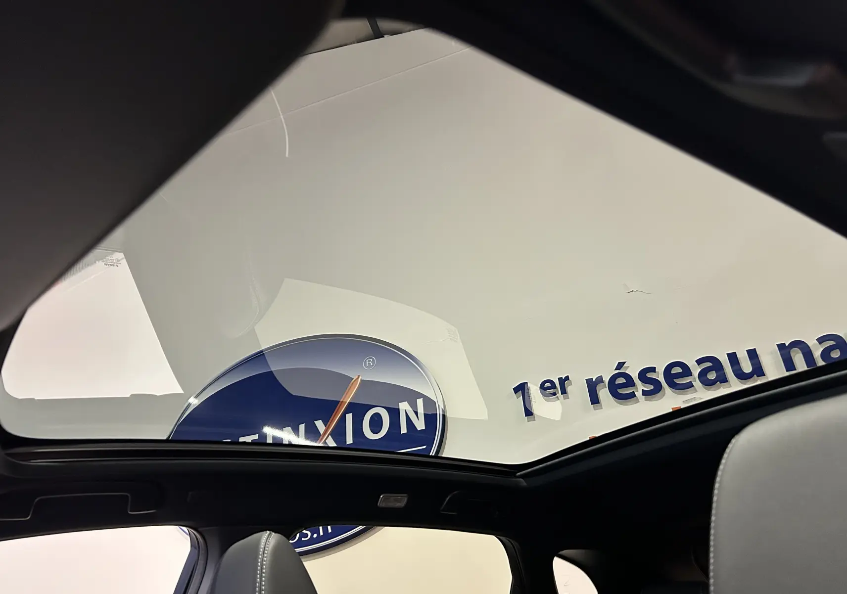 Toit panoramique en verre vu de l'intérieur d'un Nissan Qashqai gris céramique, mettant en valeur l'habitacle et la luminosité.