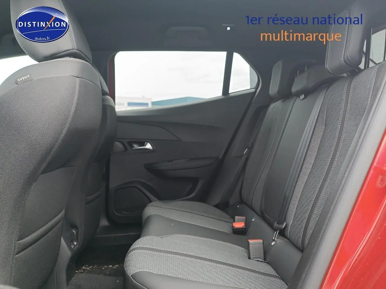 Vue latérale intérieure arrière du Peugeot 2008 rouge elixir, montrant les sièges arrière en tissu noir avec ceintures de sécurité.