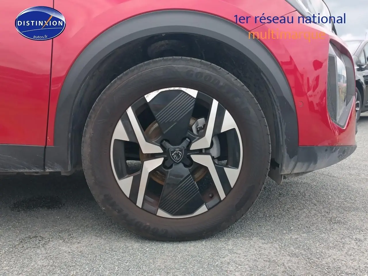 Gros plan sur la roue avant droite d’un Peugeot 2008 rouge elixir avec jante alu au design moderne.