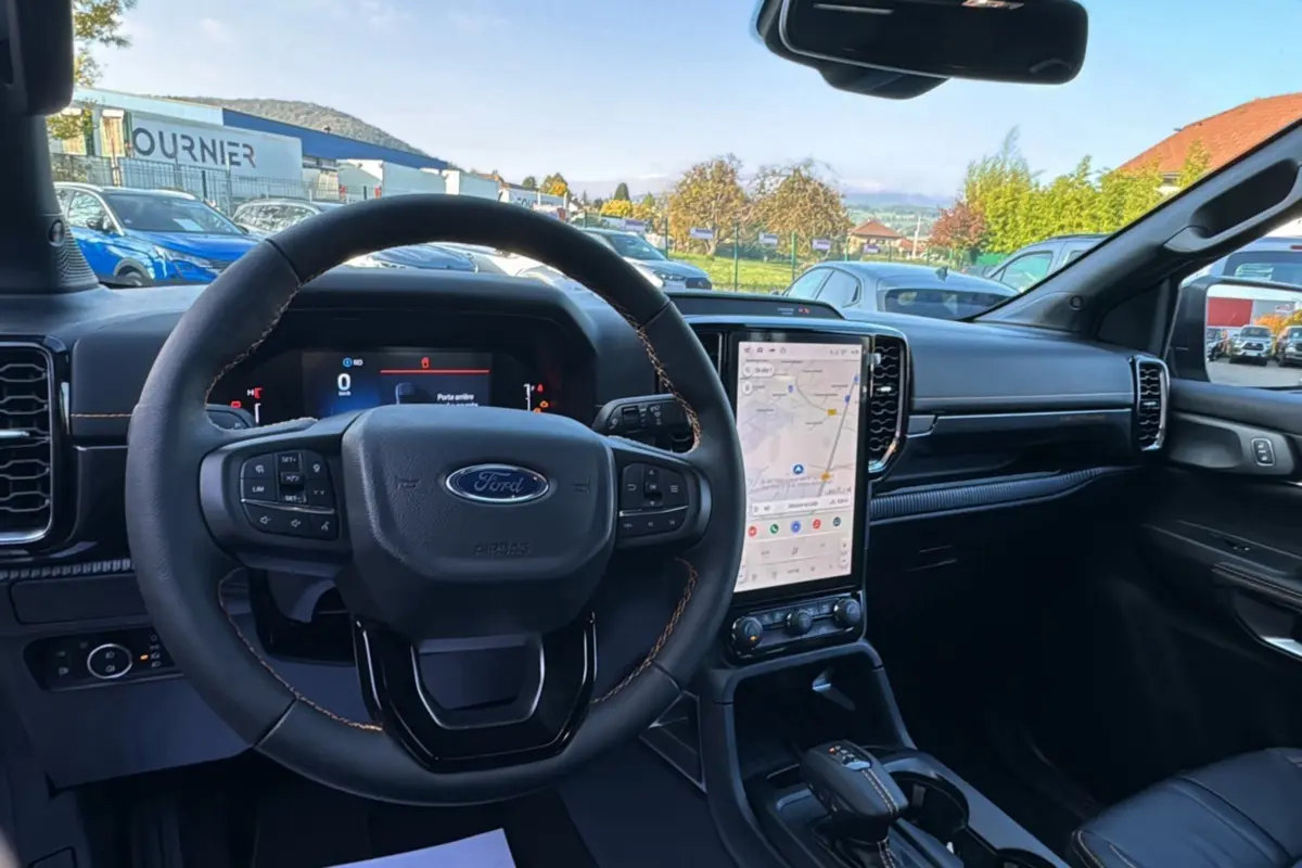 Intérieur du Ford Ranger PHEV 281 Wildtrak gris iconic, vue centrée sur le volant cuir et l'écran tactile vertical.