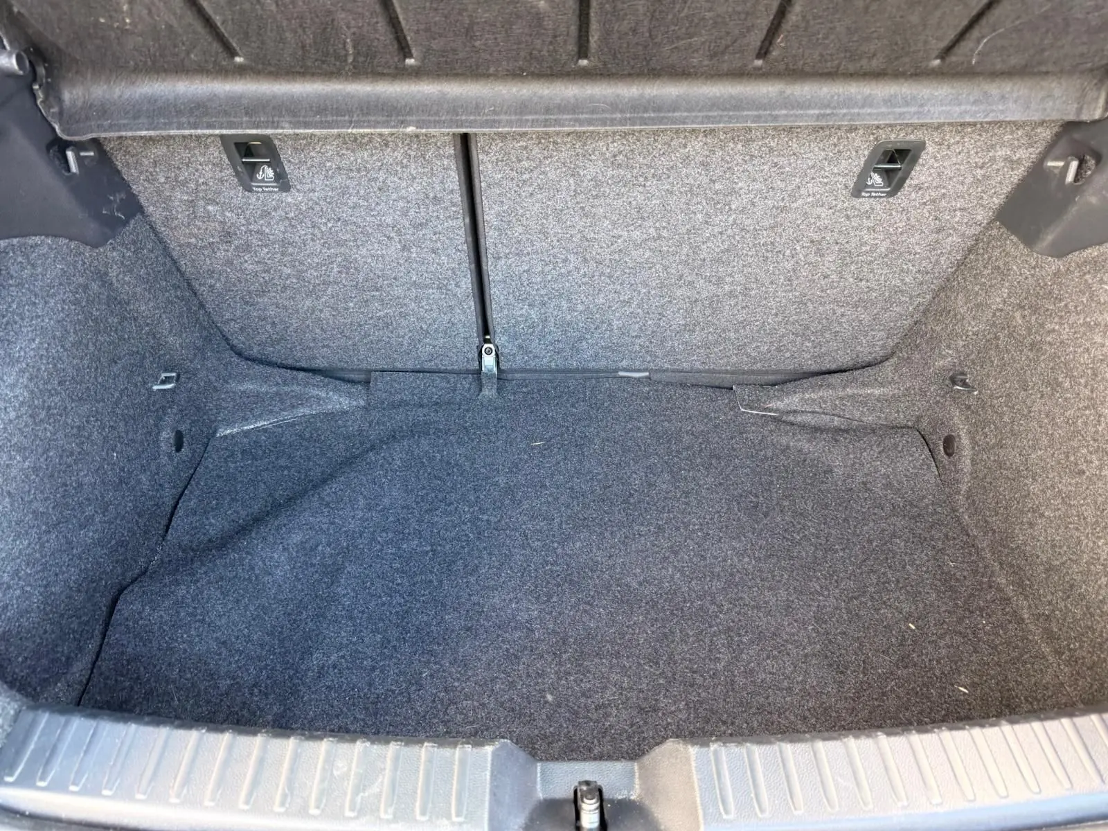 Coffre vide de la SEAT IBIZA 1.0 TSI 95 FR 2025, vue intérieure montrant la moquette grise foncée et les fixations arrière.