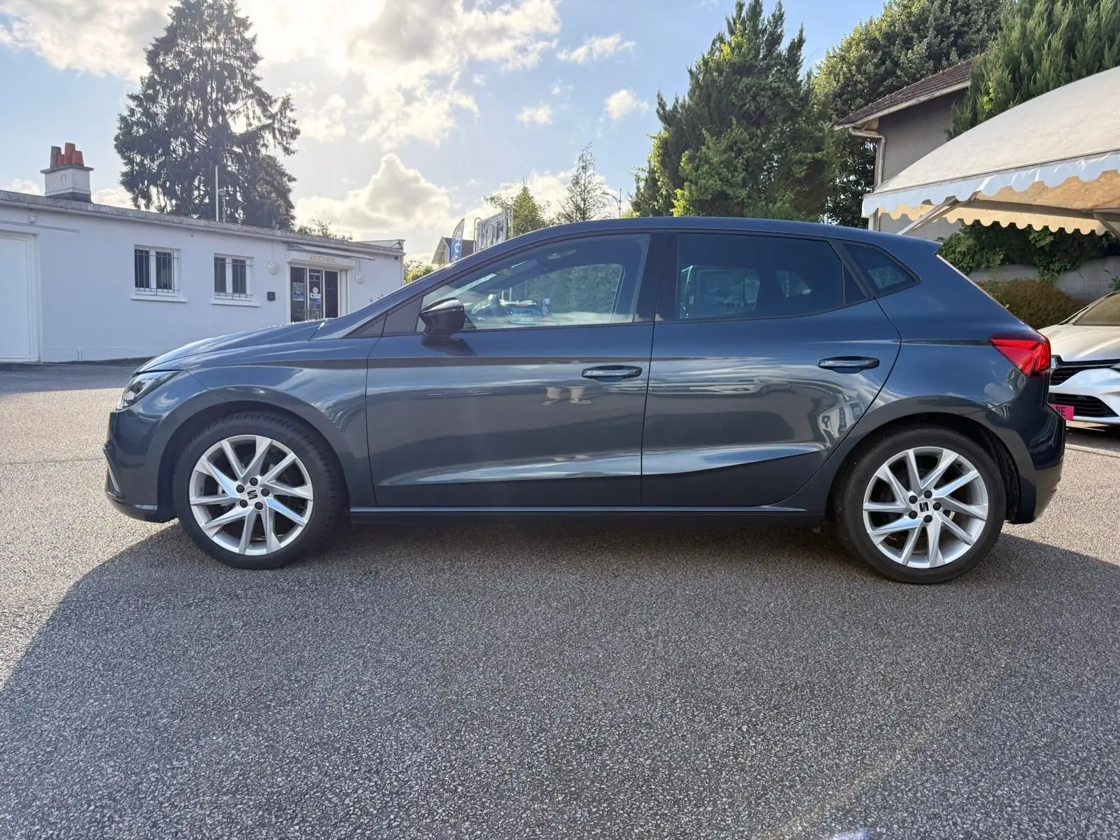 Vue de profil côté gauche d'une SEAT Ibiza 1.0 TSI 95 FR gris foncé 2025 avec jantes alliage et lignes dynamiques.