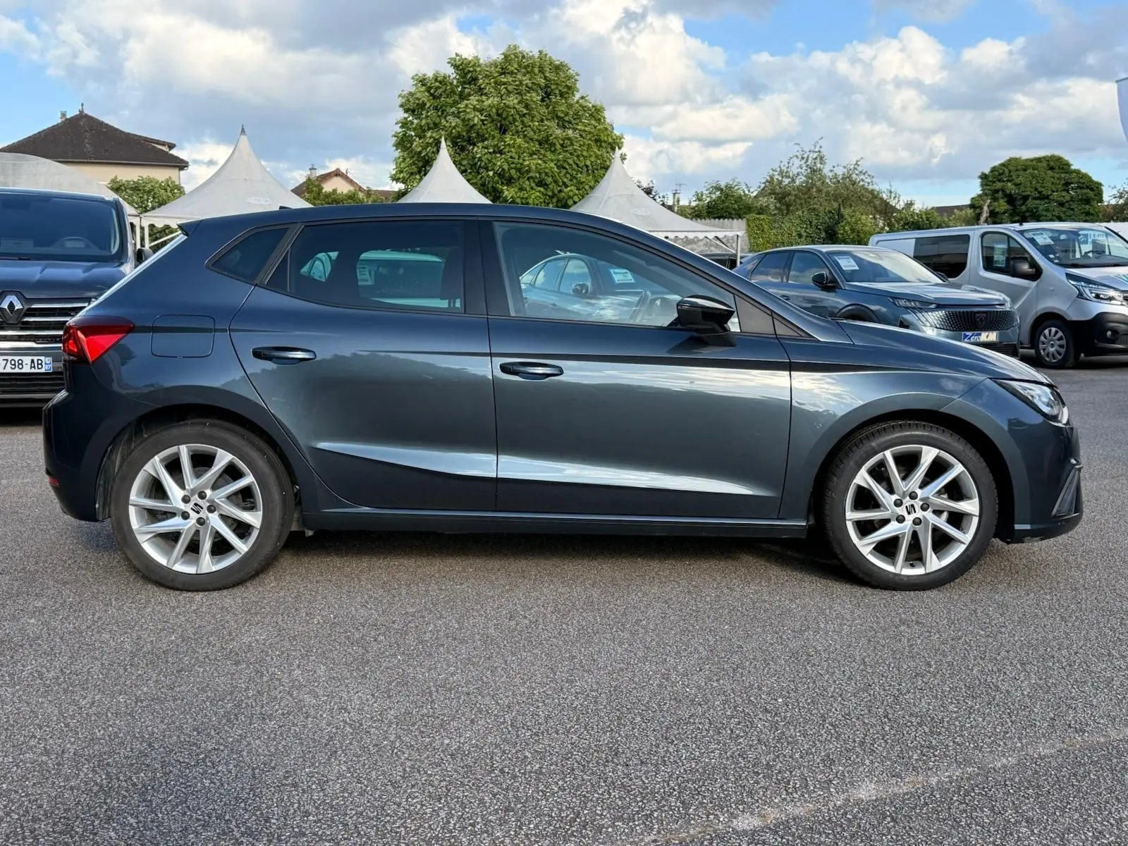 Vue de profil côté gauche d'une SEAT Ibiza 1.0 TSI 95 FR gris foncé avec jantes alliage et lignes dynamiques.