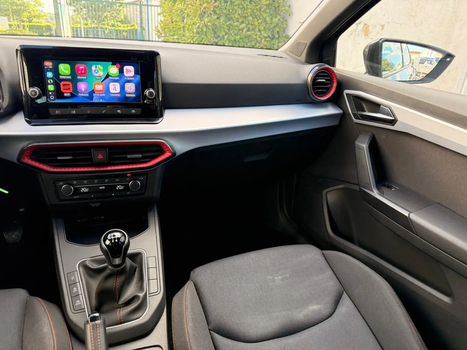 Intérieur de la SEAT Ibiza 1.0 TSI 95 FR 2025, vue côté passager, tableau de bord gris avec touches rouges et écran tactile.