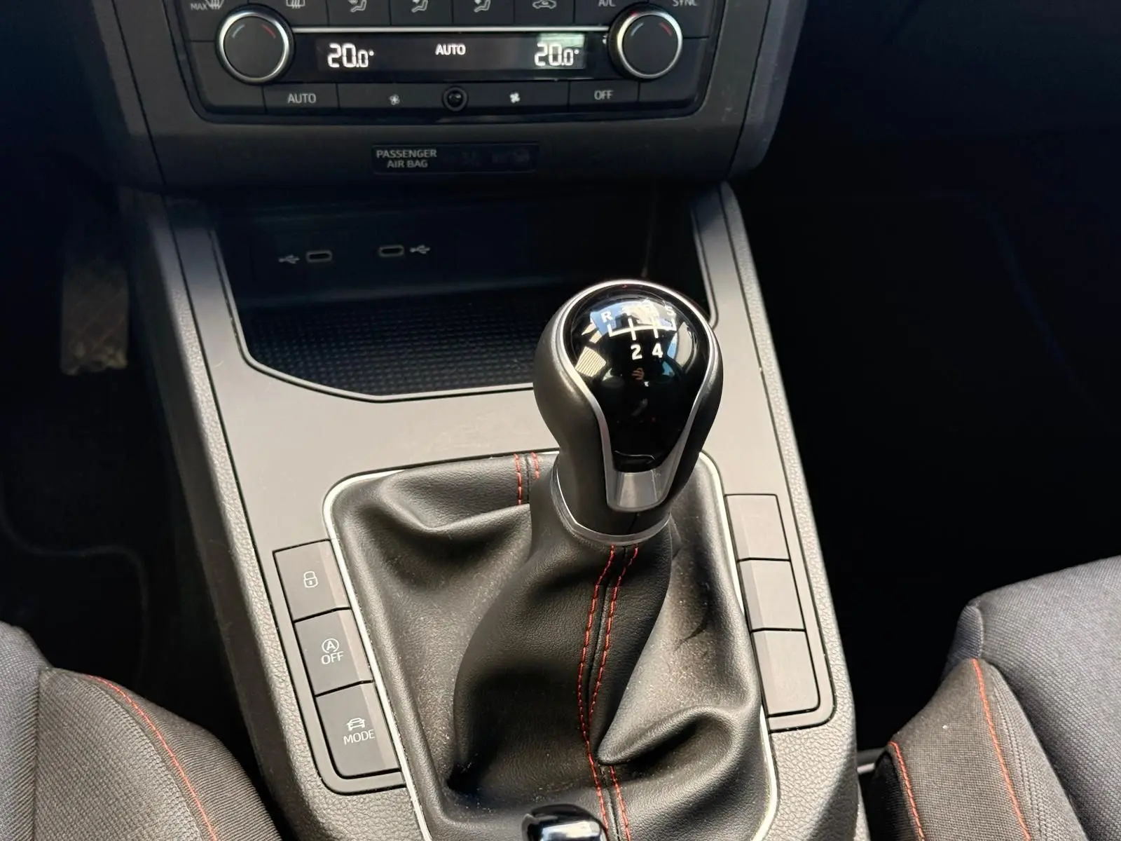 Le levier de vitesse manuel noir avec surpiqûres rouges dans l'habitacle d'une SEAT IBIZA gris foncé 2025.