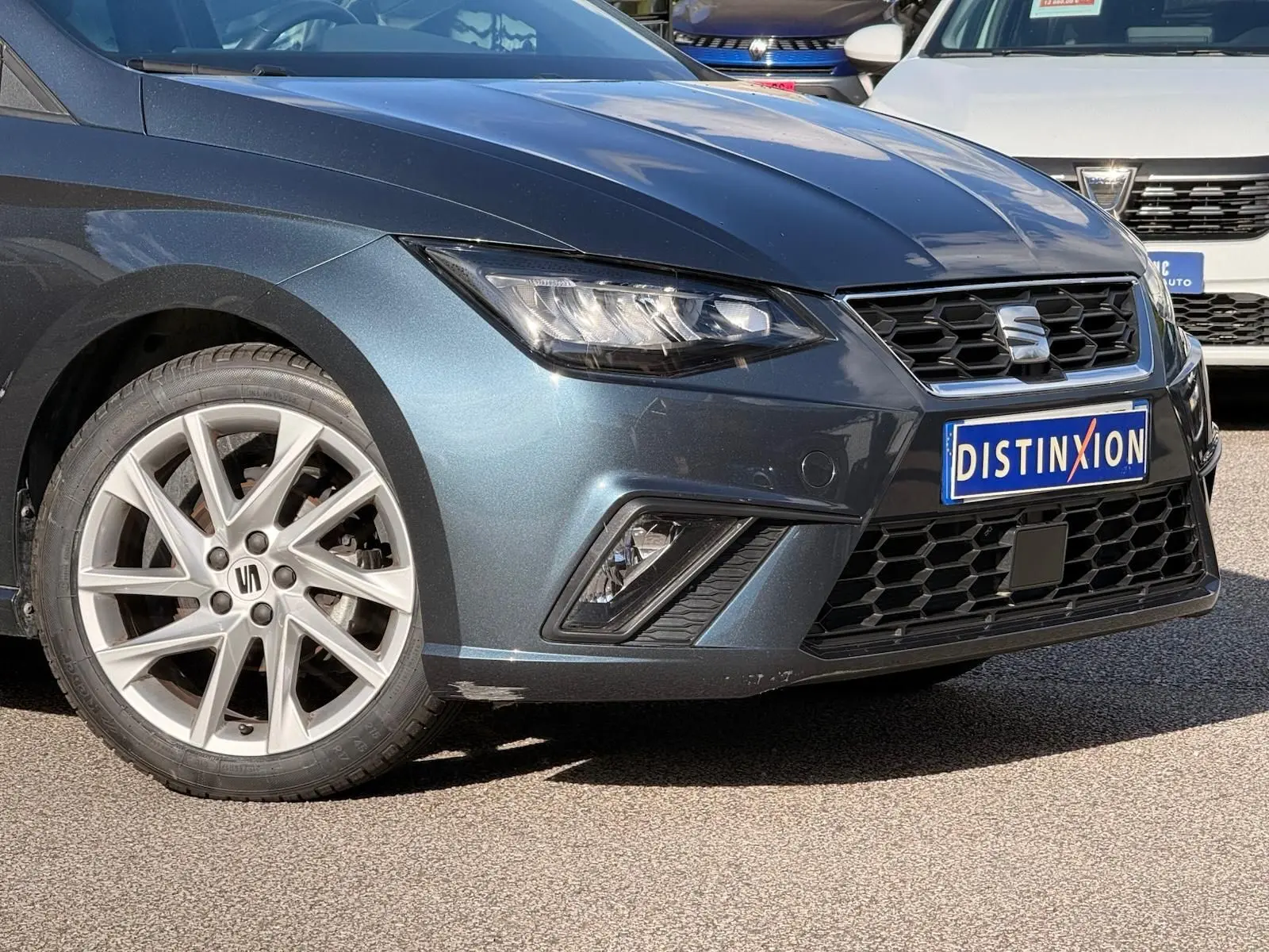 Vue 3/4 avant gauche d'une SEAT Ibiza 1.0 TSI 95 FR gris foncé avec jantes alliage et calandre hexagonale noire.
