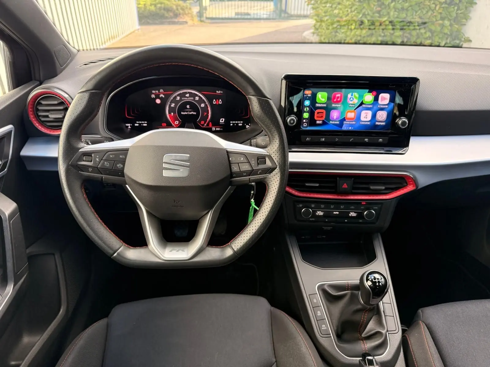 Vue intérieure frontale du poste de conduite de la SEAT Ibiza 1.0 TSI 95 FR 2025, volant sport, écran tactile et levier de vitesses manuel.