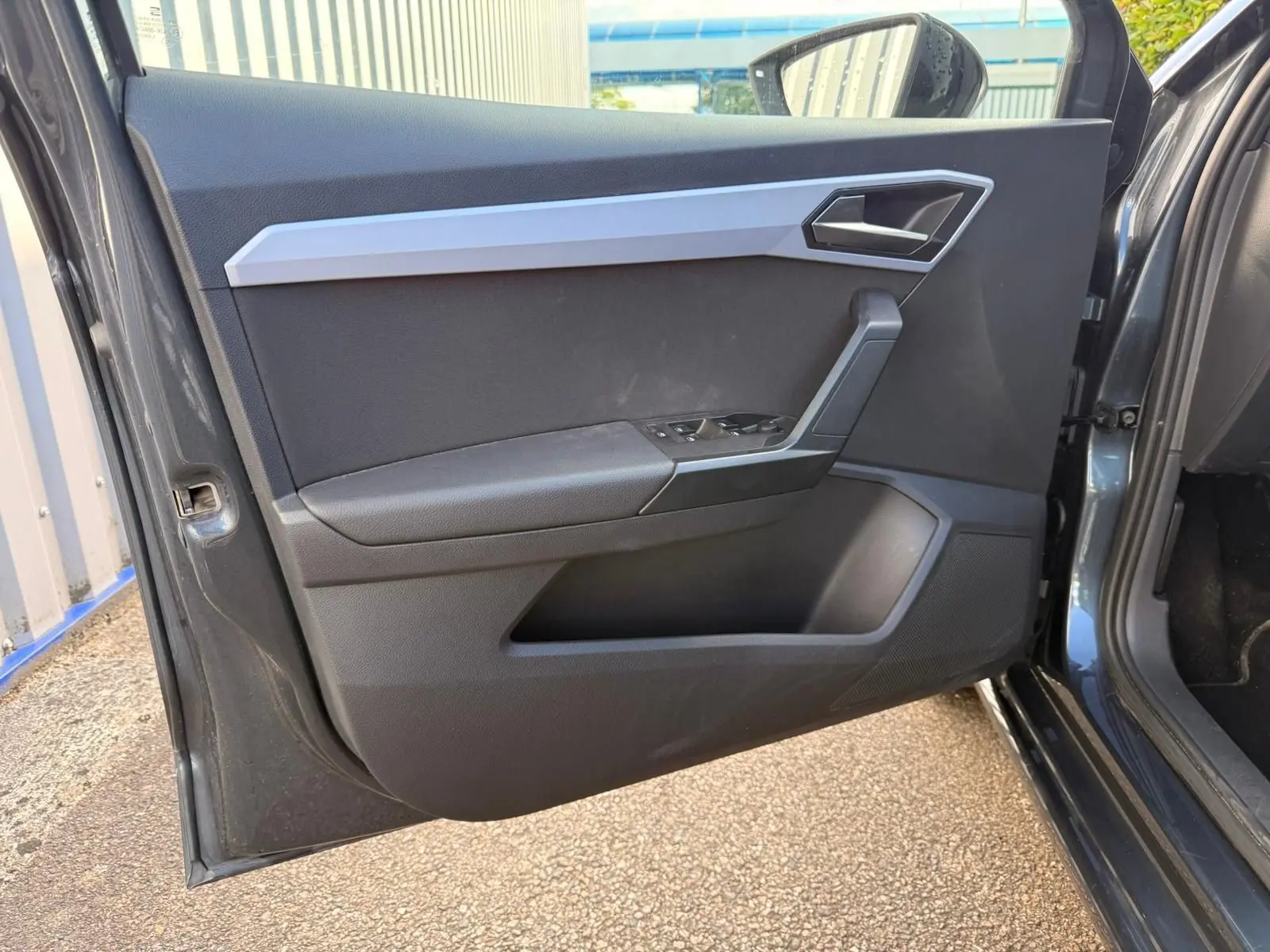 Vue intérieure de la porte avant gauche d’une SEAT Ibiza 1.0 TSI 95 FR gris foncé avec garniture noire et insert argenté.