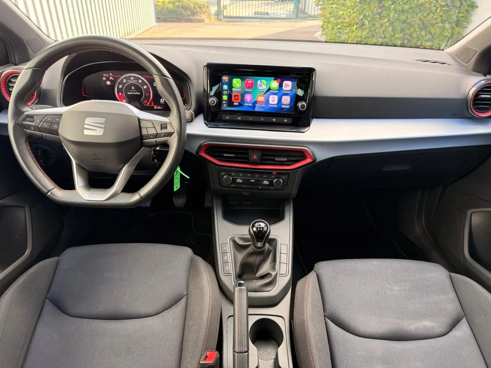 Vue intérieure avant de la SEAT Ibiza 1.0 TSI 95 FR 2025, tableau de bord avec écran tactile et volant sport noir avec surpiqûres rouges.