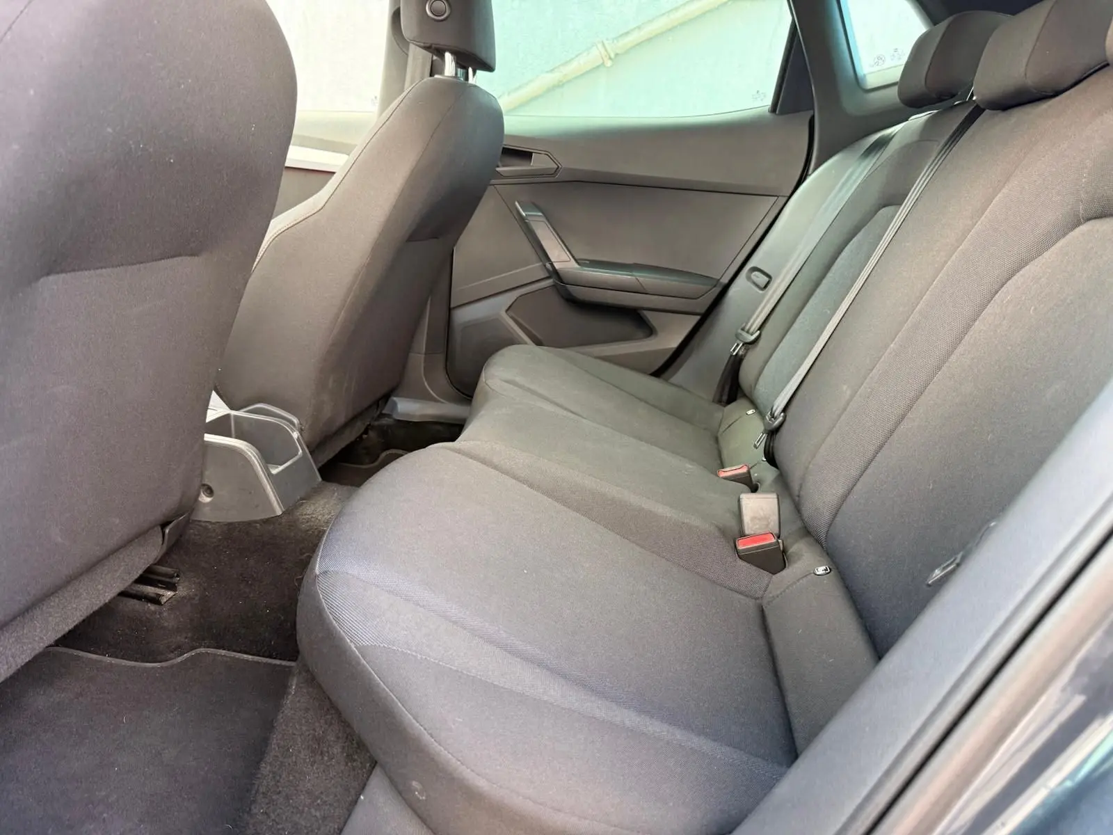 Vue intérieure côté droit des sièges arrière gris foncé d'une SEAT IBIZA 1.0 TSI 95 FR 2025, tissu sobre et ceintures visibles.