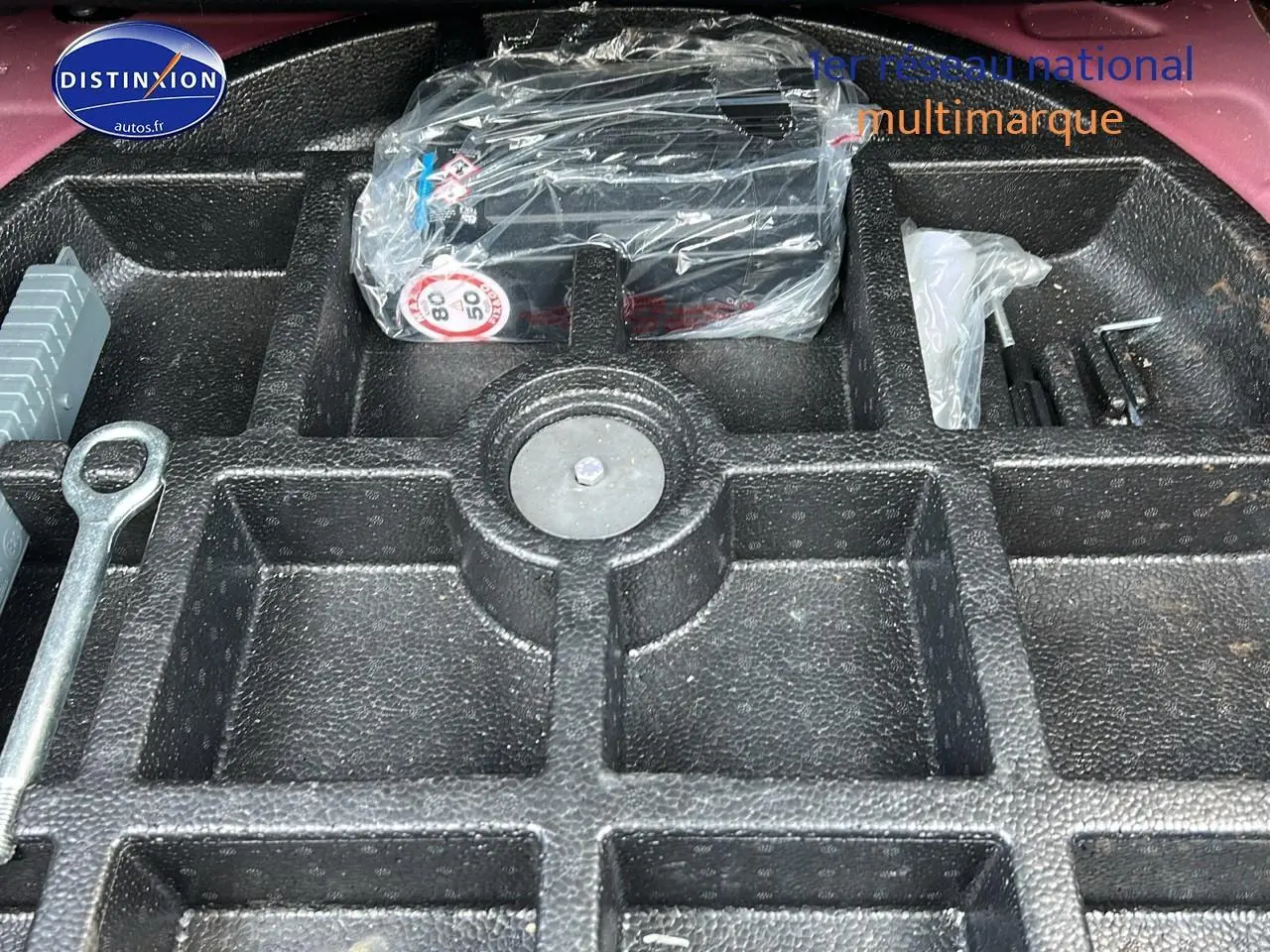 Coffre ouvert d'une Fiat 500X rouge montrant le rangement en mousse pour outils et kit anti-crevaison.